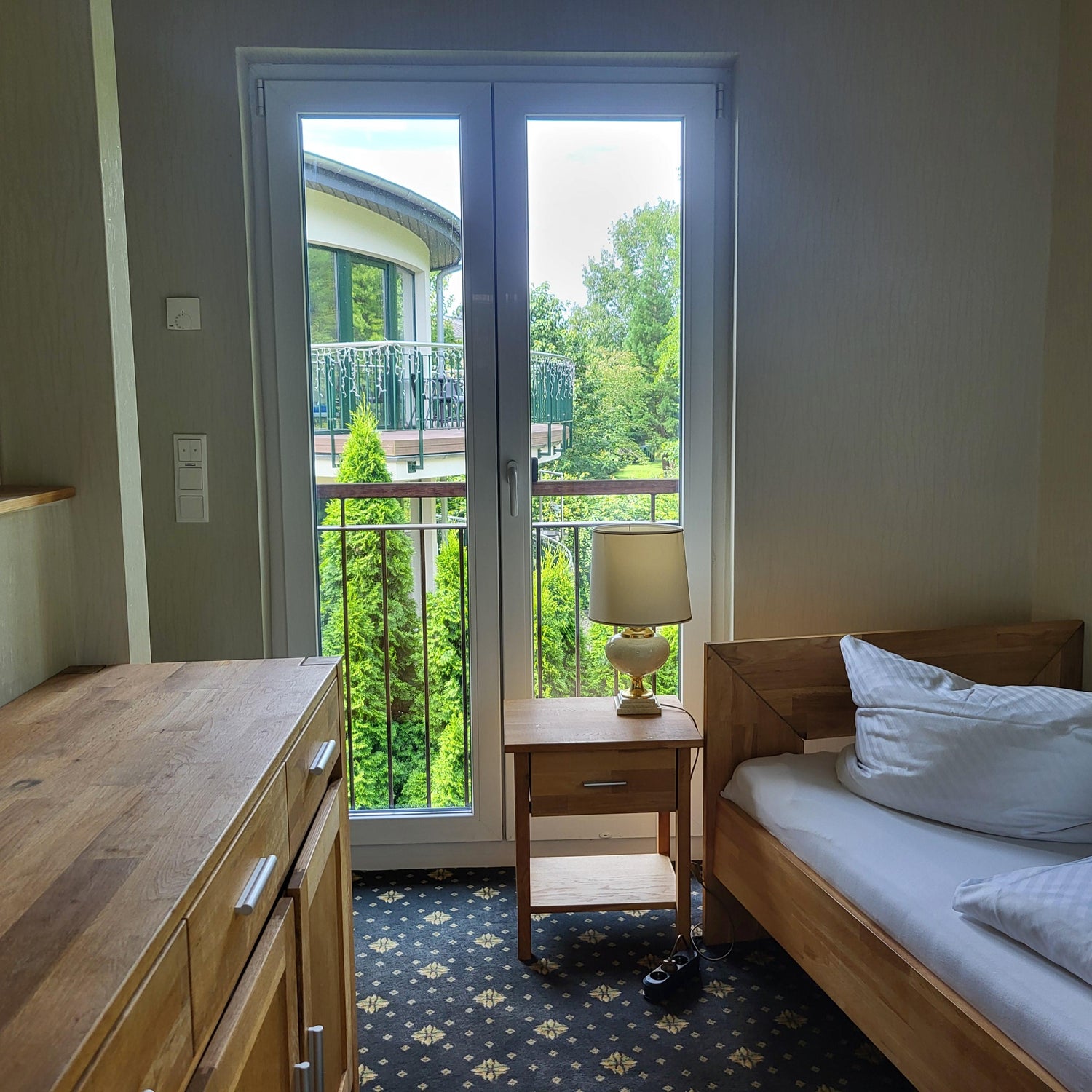 Einzelzimmer im Haus 2 - Schlafzimmer mit Einzelbett und Kommode - Blick auf das Nachbargebäude