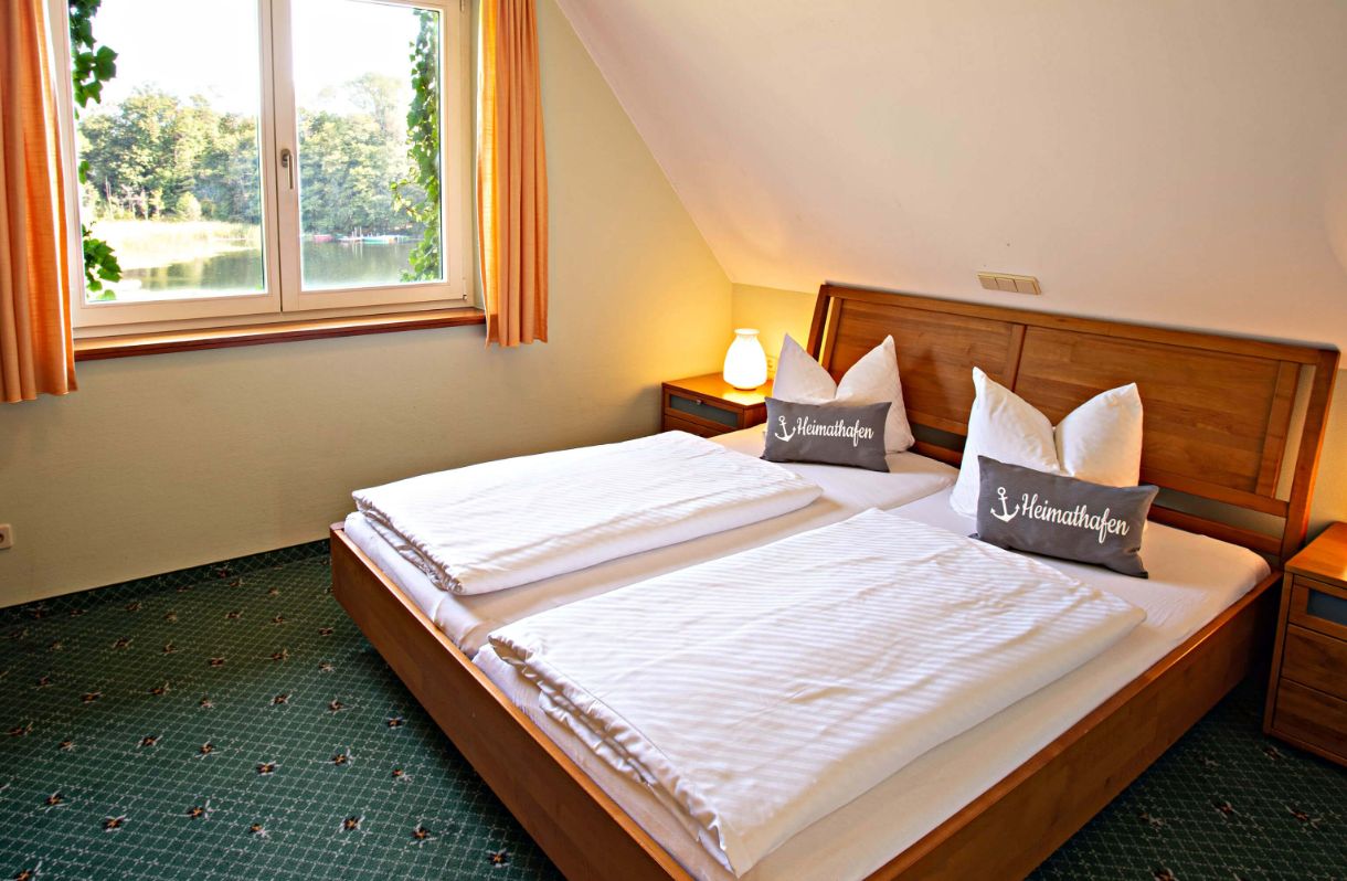 Apartment Fischhaus: Schlafzimmer mit Doppelbett, Dachschräge, Blick auf Glubigsee