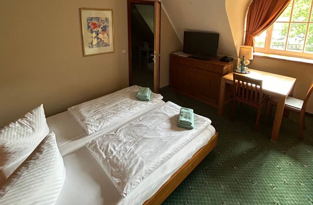 Fischhaus OG: Einzelzimmer mit Bett, Tisch, 2 Stühlen & Kommode mit TV