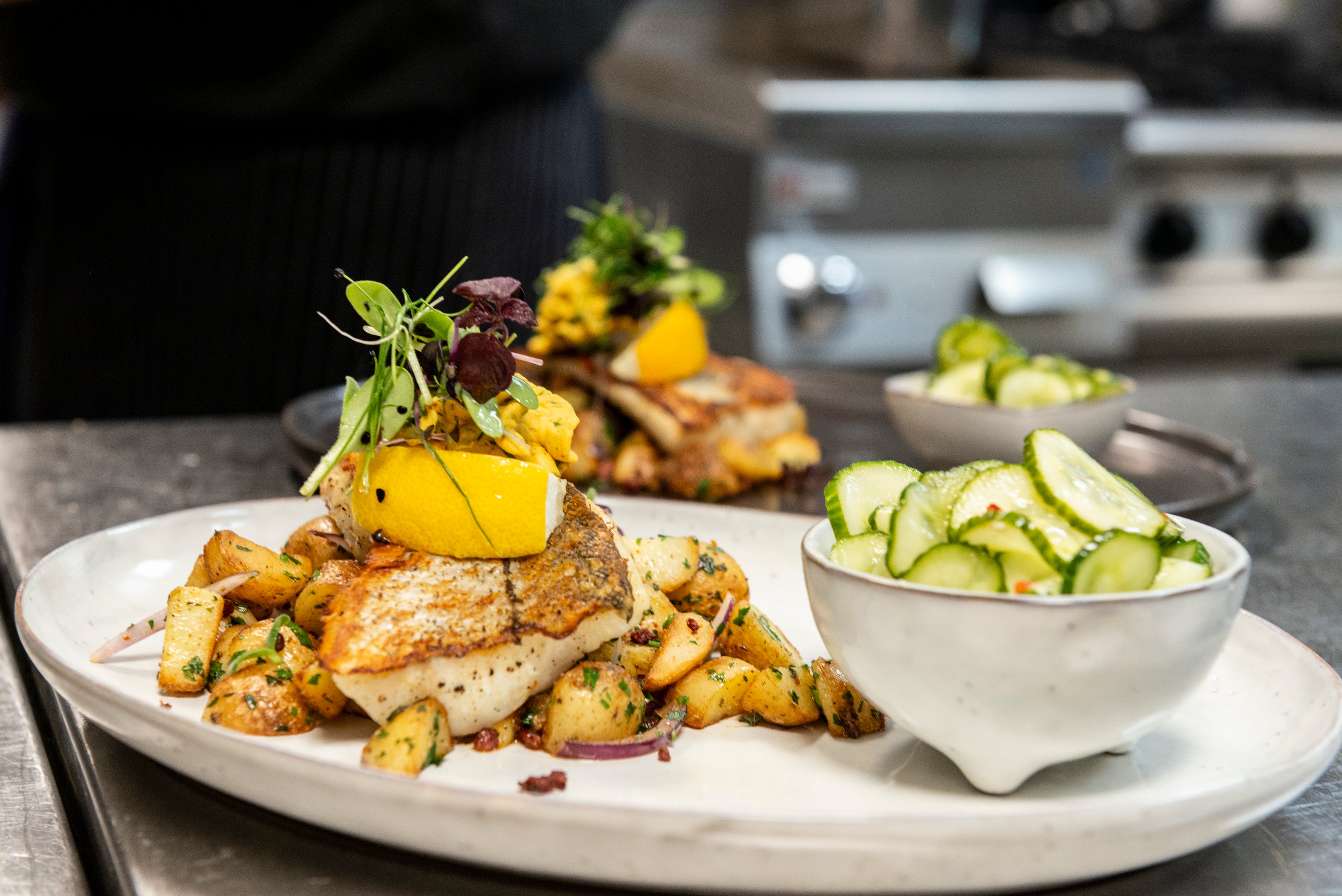 Fischgericht - gebratenes Fischfilet auf Bratkartoffeln mit Gurkensalat